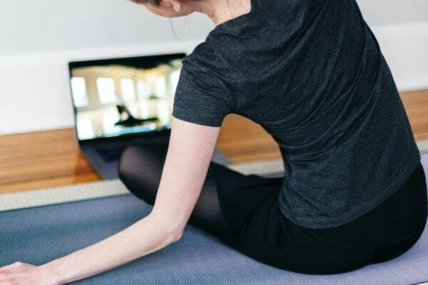 woman in black t-shirt and black pants lying on black yoga mat