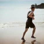 Man Wearing Black Tank Top and Running on Seashore